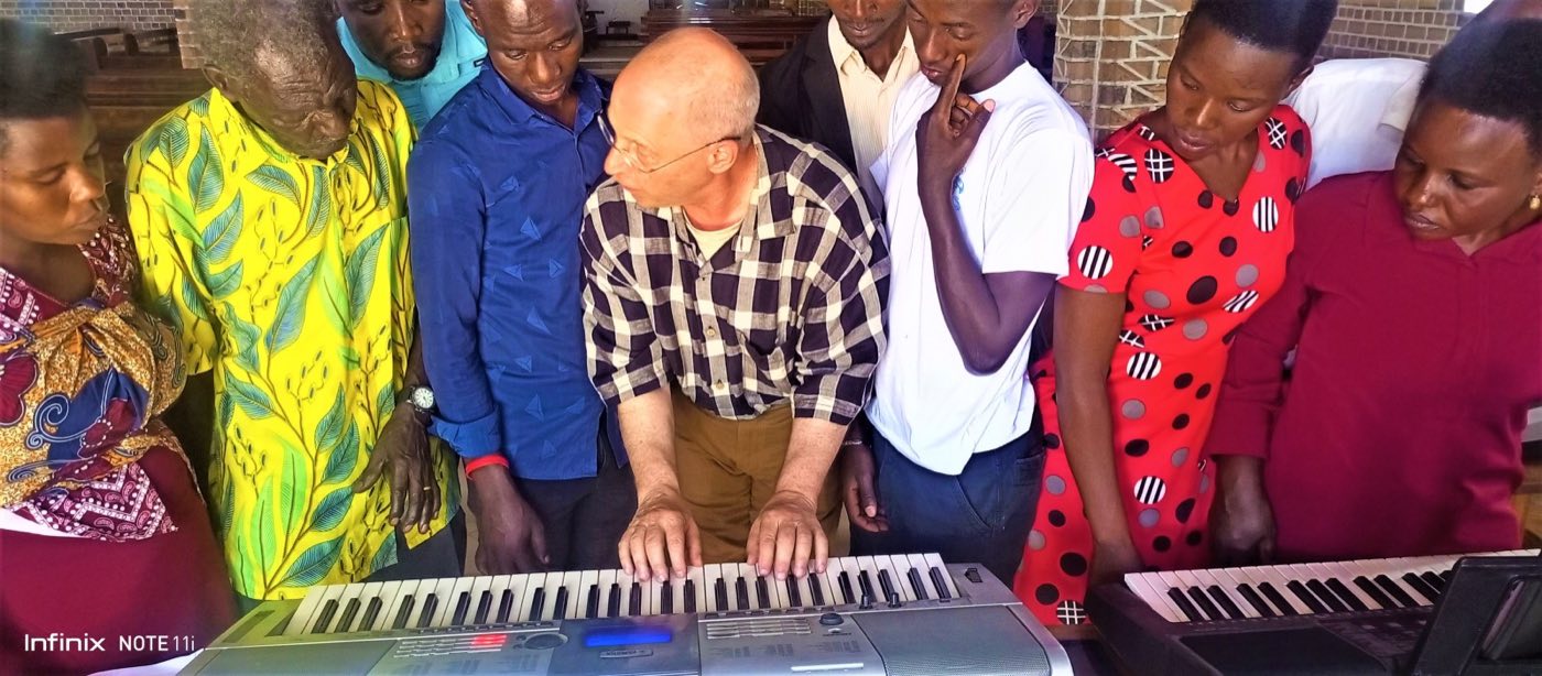 Volunteer Joshua Stone teaching keyboard to a group in Kabwohe